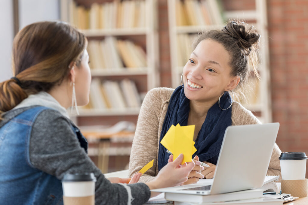 two female college students using notecards to study.