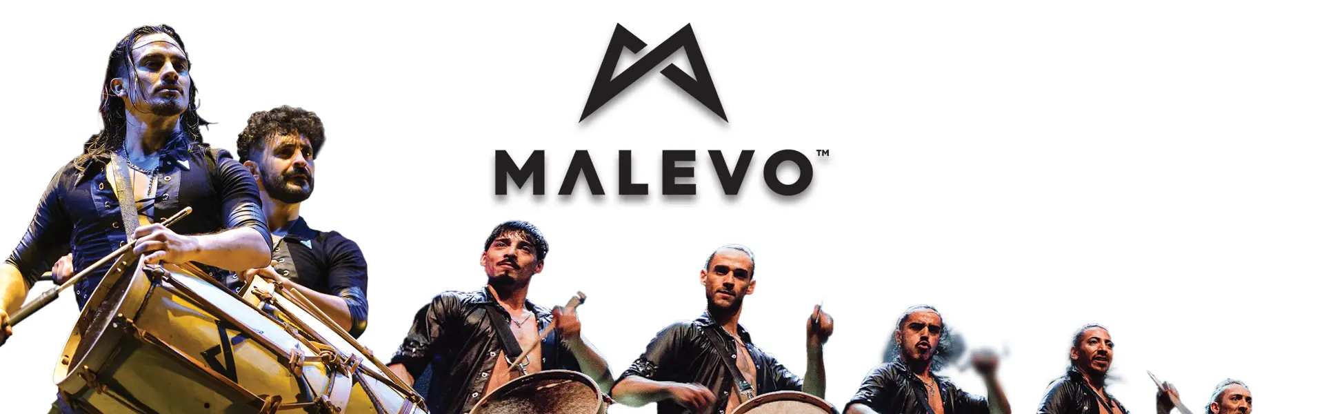 Men standing in a line playing drums that are slung over their shoulders.