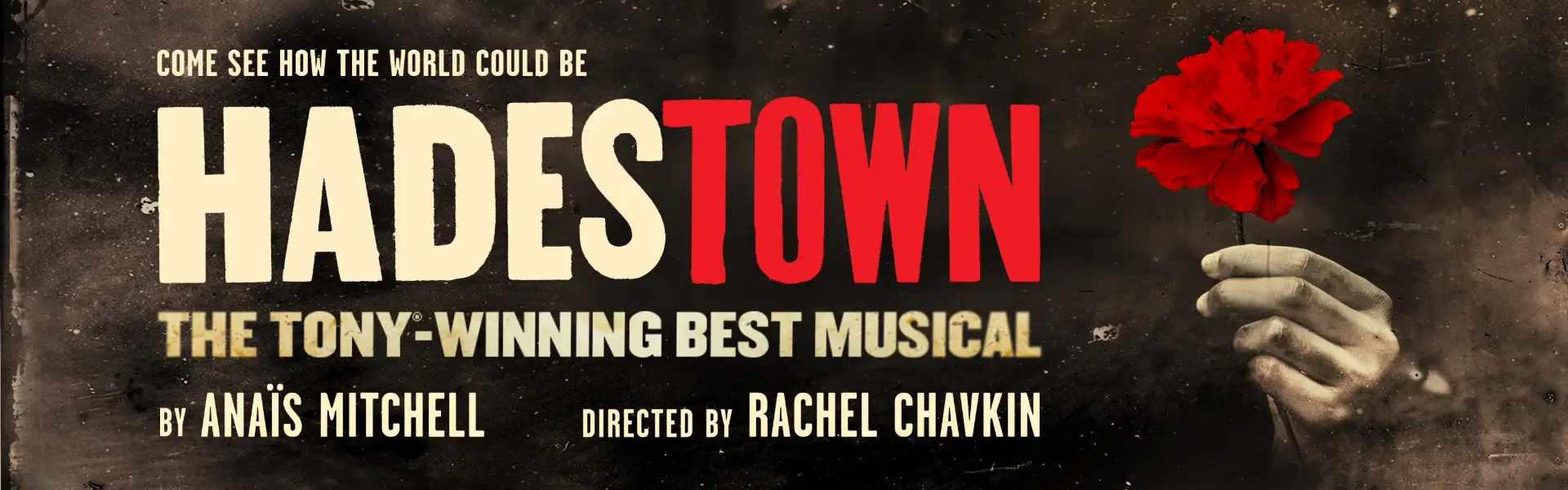 Promotional image for 'Hadestown,' the Tony-winning best musical by Anaïs Mitchell, directed by Rachel Chavkin. The image features the title in bold letters with the tagline 'Come See How the World Could Be,' and a hand holding a bright red flower against a dark, textured background.