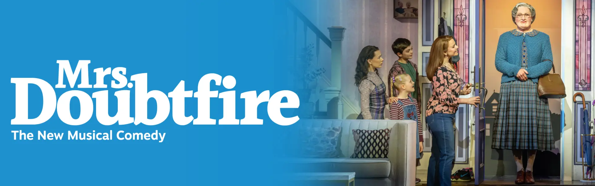Stage scene from the Mrs. Doubtfire musical with the main character greeting a family at the door, set in a colorful home interior.