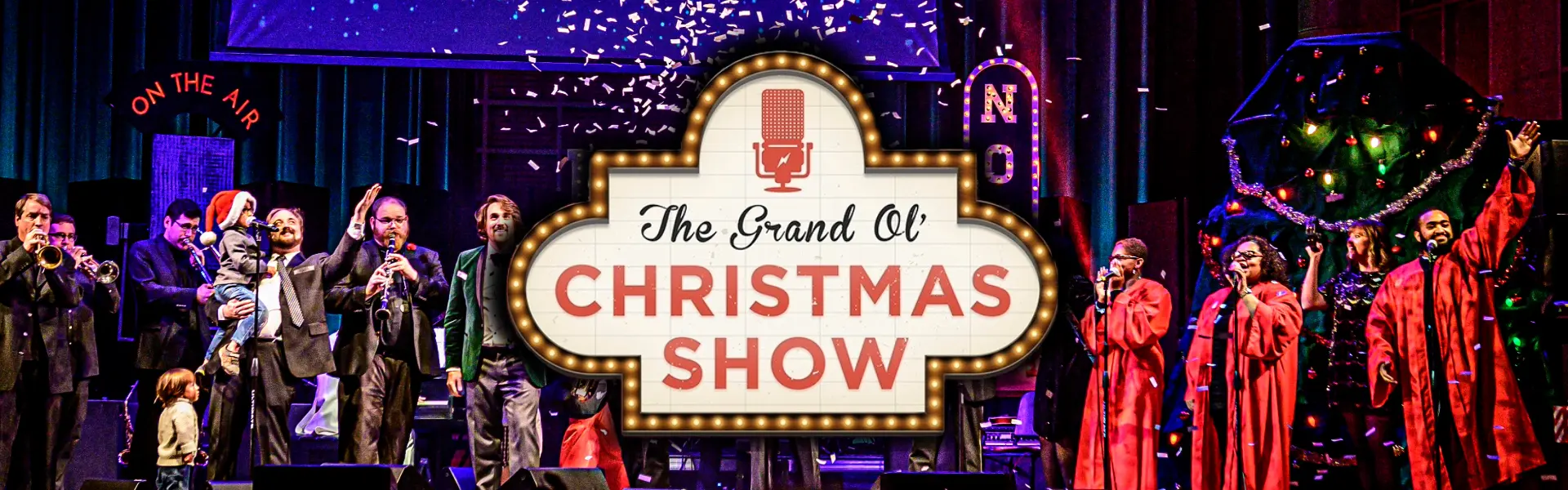 Musicians and singers perform a vintage-style holiday variety show on a decorated stage with Christmas trees and lights.