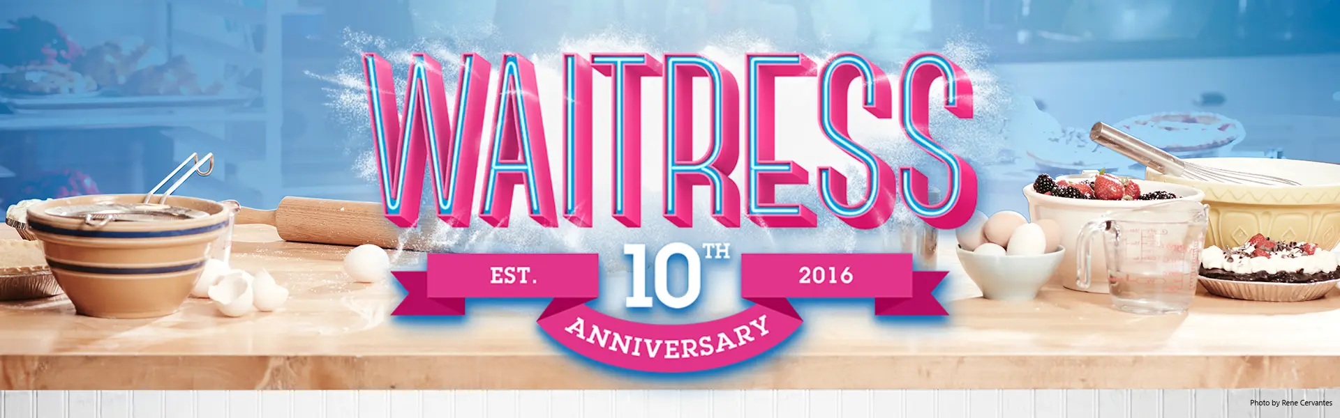 Waitress 10th Anniversary promotional image featuring baking ingredients and pies on a kitchen counter.
