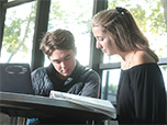 Two students studying; sitting by a window