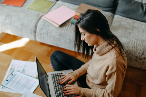Picture of woman working on computer surrounded by paper materials