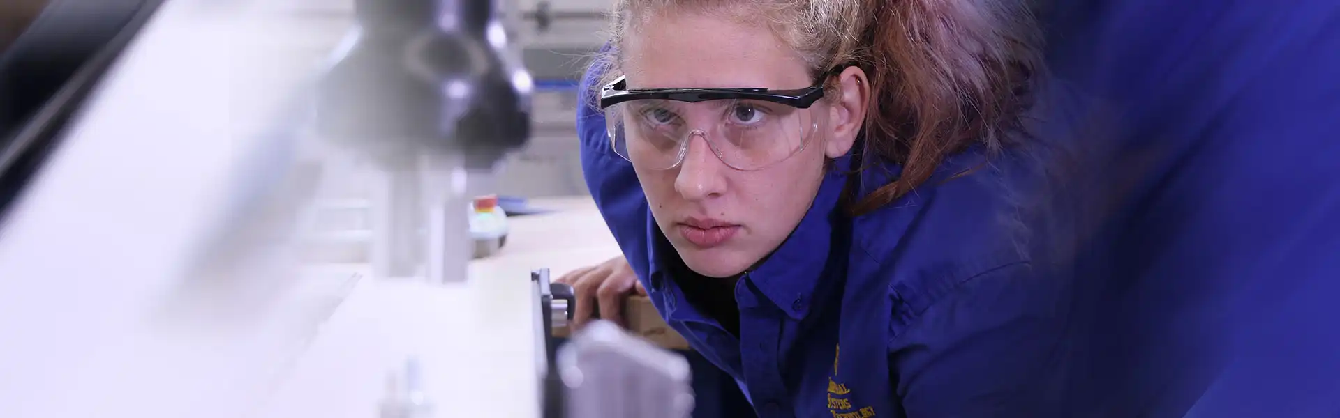 Photo of a female student working with state-of-the-art robot in the IST lab.