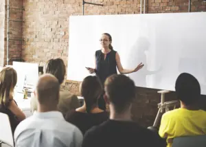 Woman standing in front of a white board teaching a class