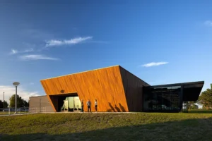 Modern wood-paneled building exterior at sunset with students standing outside.