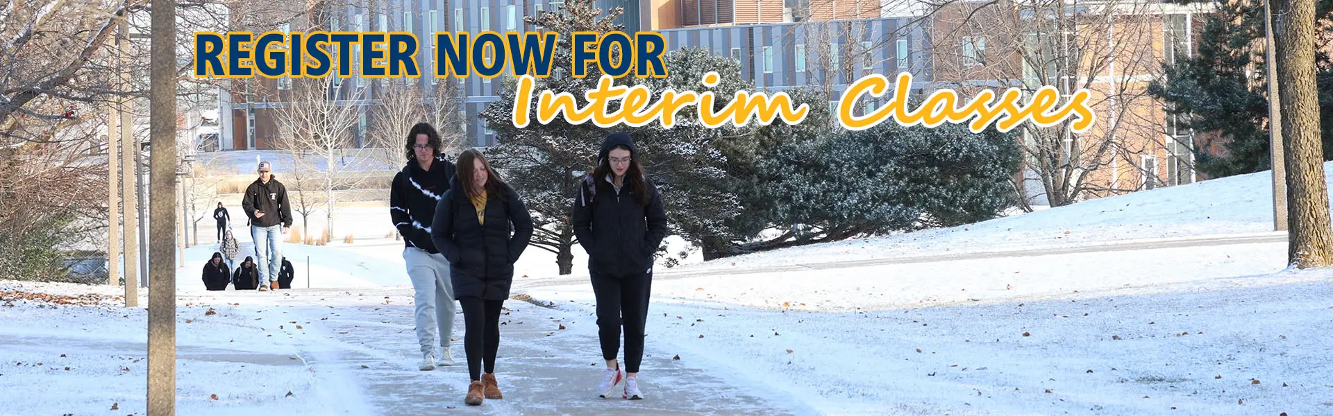 Picture of students in winter hats and coats standing between trees covered in snow, with text "Register for Winterim Classes"
