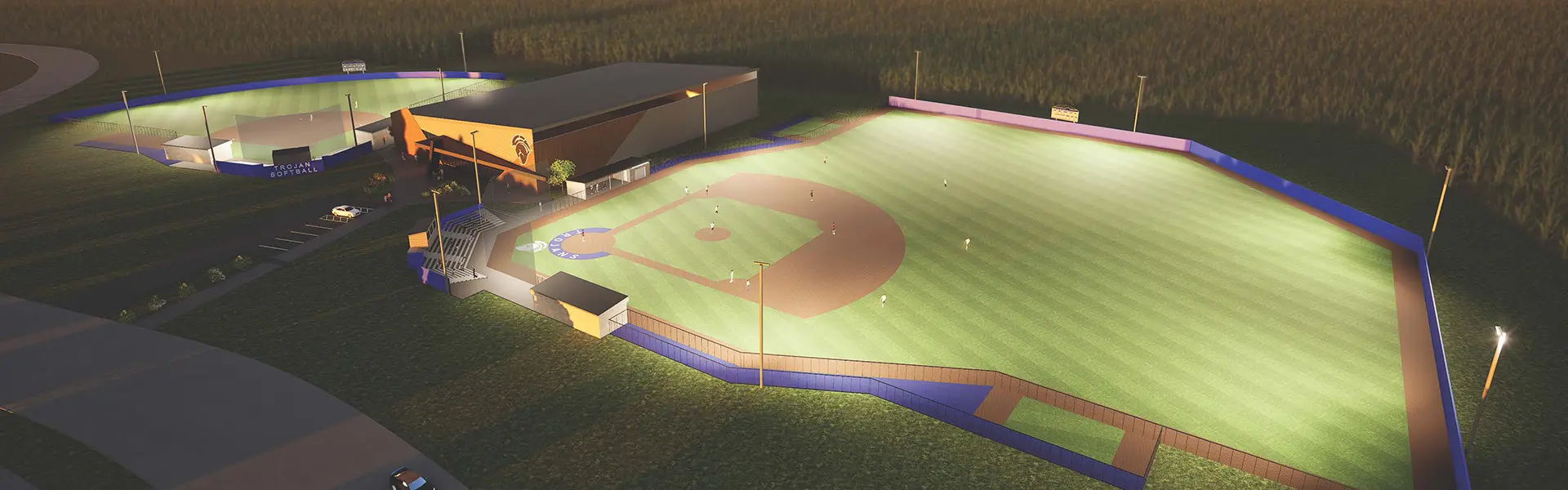 Aerial rendering of an illuminated baseball and softball complex at dusk, showing two lit fields, stadium seating, and a modern athletic facility building.