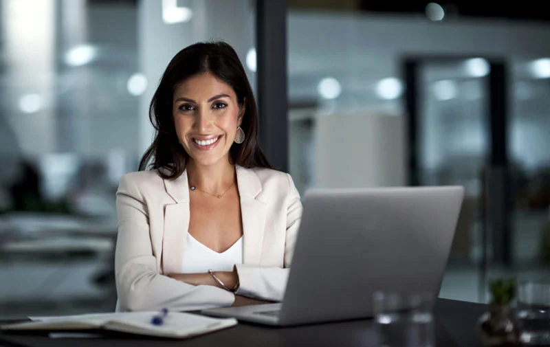 Picture of woman working on laptop, staring at camera