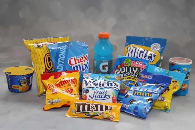 Picture of various food and drink items including includes Chips, Chex Mix, Bugles, Instant Macaroni and Cheese, Pringles, Starburst, Fuit Snacks, Mini Oreo, M&Ms, and Gatorade