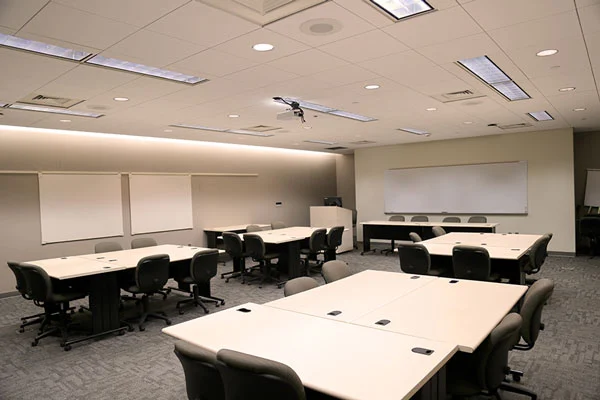 Photo of meeting room PC224 showing tables, desks, projector, white boards, and command station