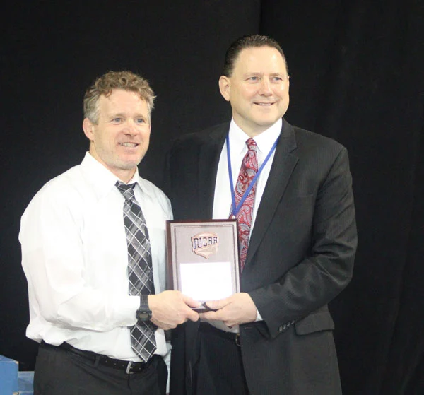 Picture of NIACC Wrestling coach Steve Kelly receiving 2022 NJCAA award